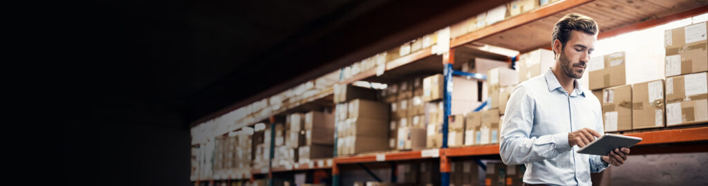 Man in a warehouse looking at his laptop. 