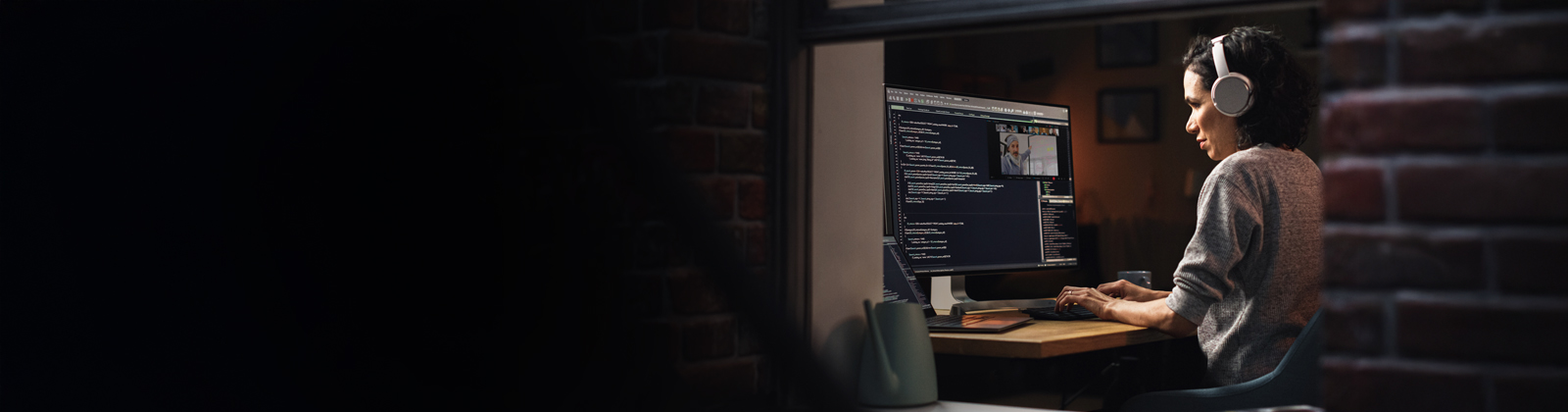 Woman looking at her computer with her headphones on.